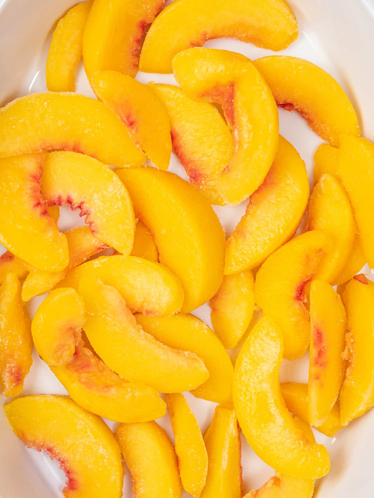 Close up of sliced peaches in the bottom of a baking dish.