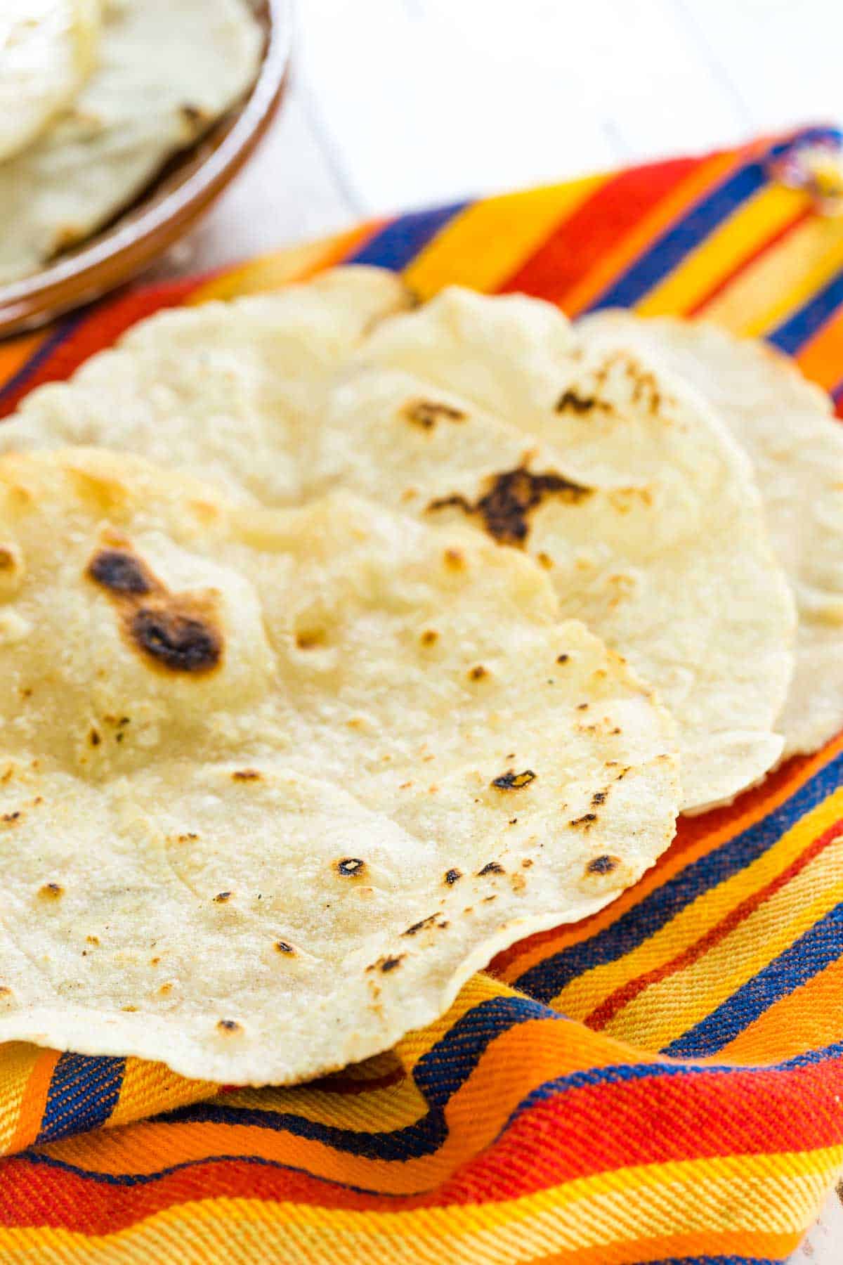 Gluten free tortillas laid out on a colorful striped cloth.