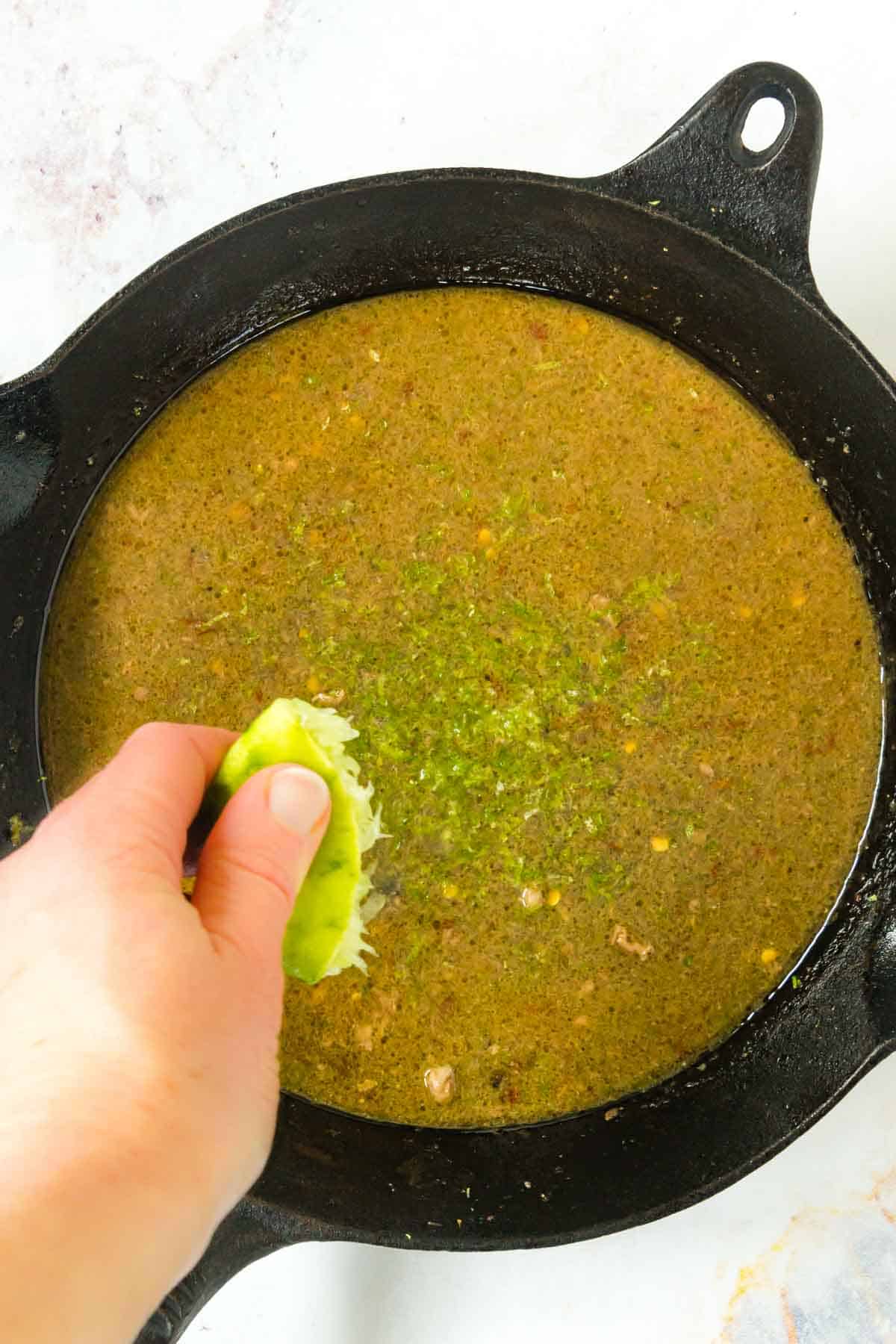 Squeezing lime juice into a cast iron pan.
