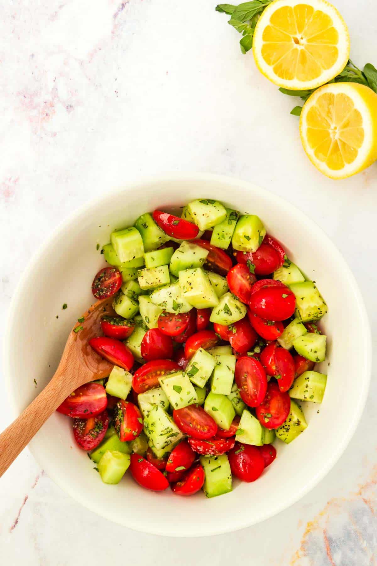 Tomatoes and cucumbers tossed with the dressing in a bowl.