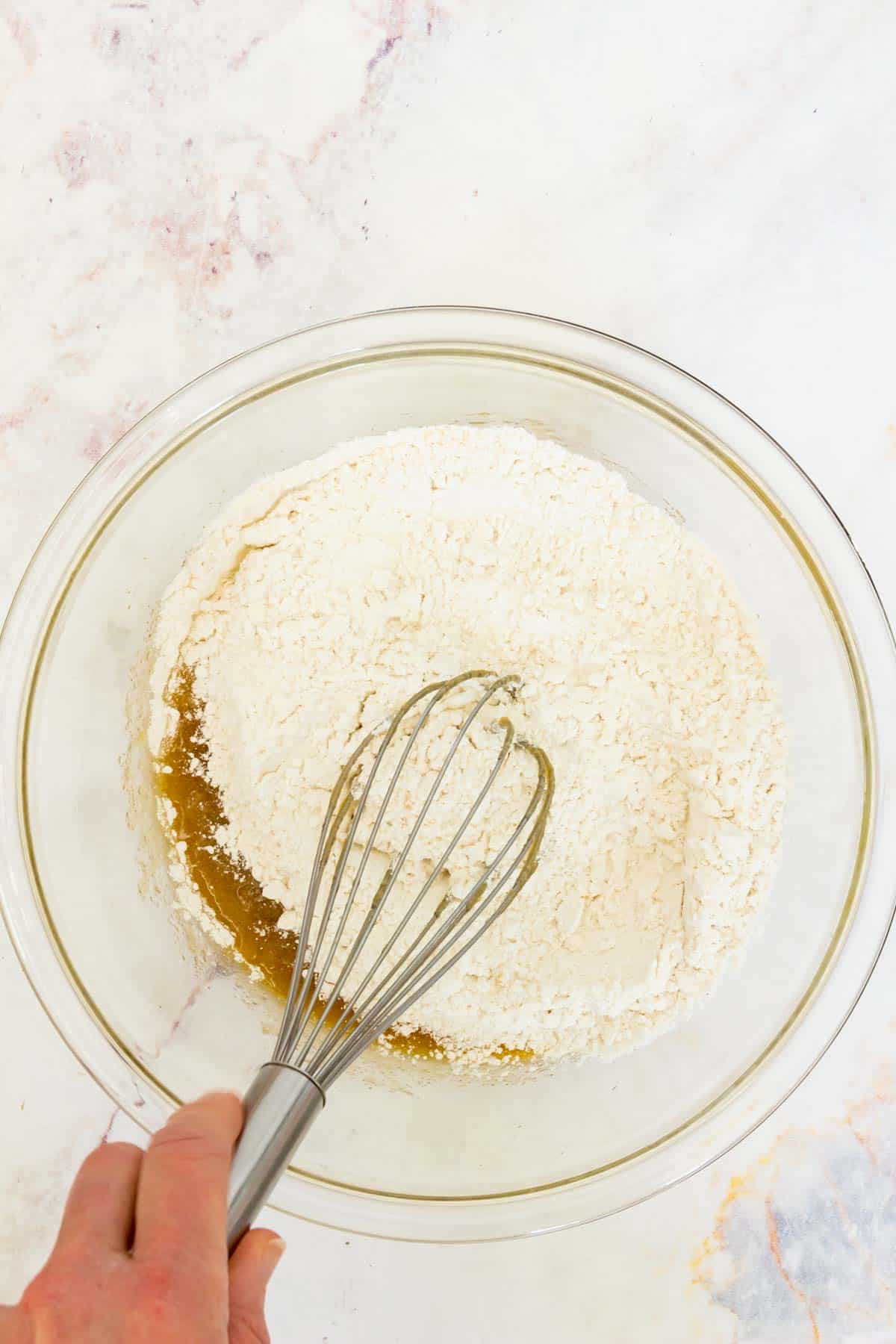 Flour is whisked into a bowl with the wet cookie dough ingredients.