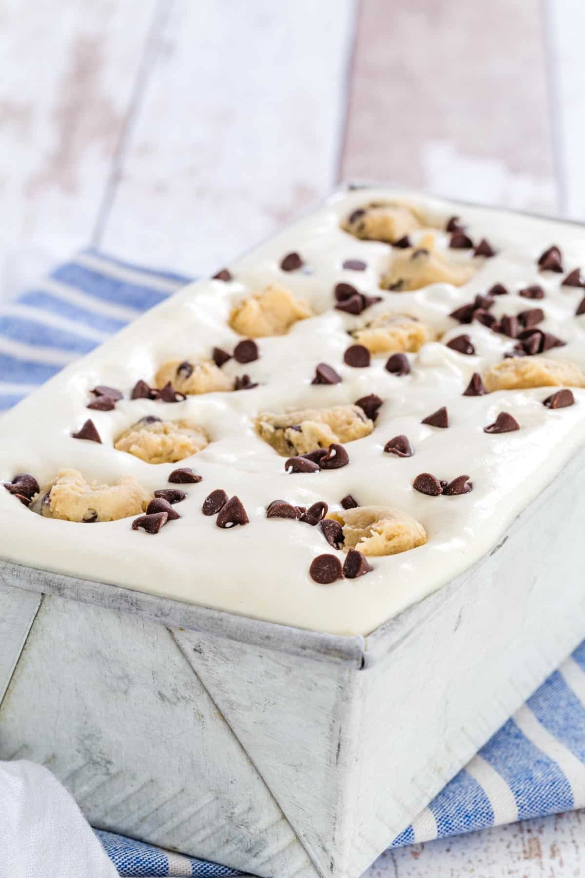 Chocolate chip cookie dough no-churn ice cream in a metal loaf pan, topped with chunks of cookie dough and chocolate chips.