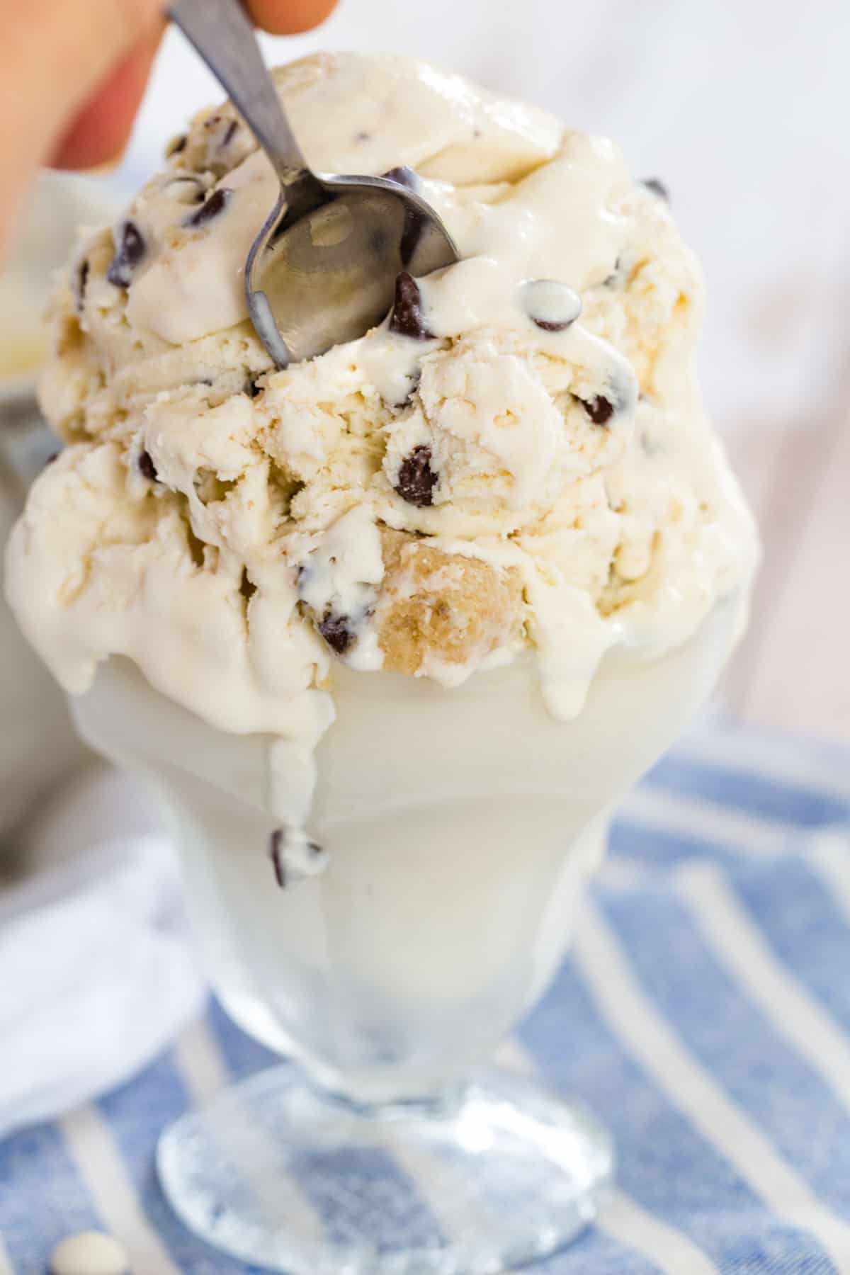 Chocolate chip cookie dough no-churn ice cream served in a fountain glass, with melted ice cream running down the sides.