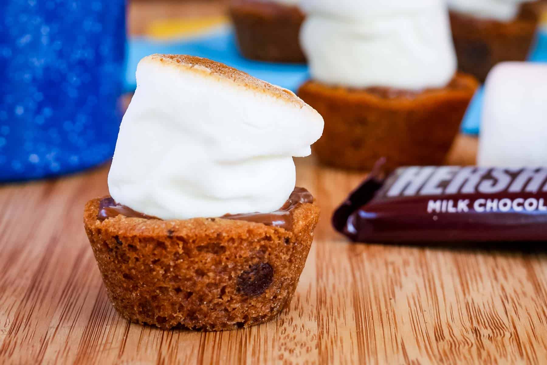 A close-up of a S'Mores Cookie Cup with a wrapped bar of chocolate in the background