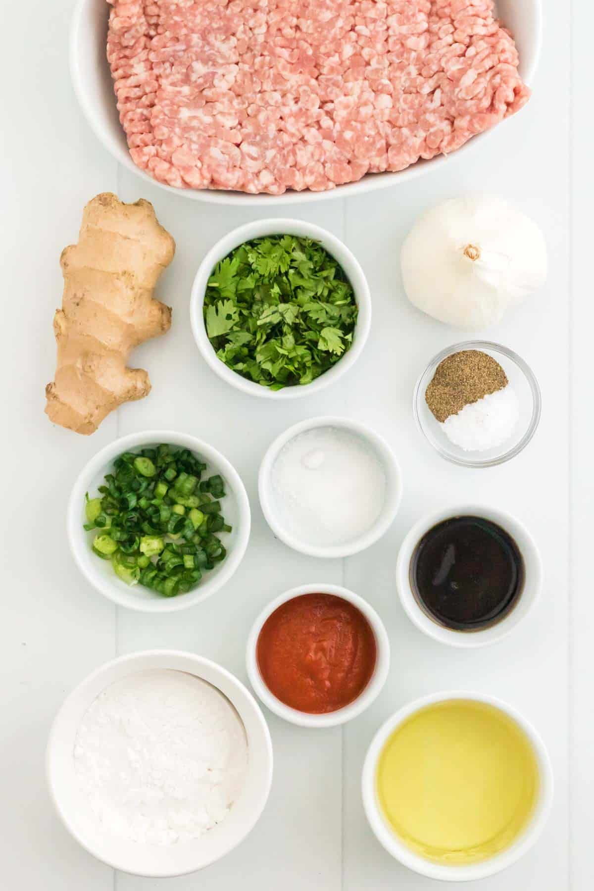 The ingredients for the pork meatballs laid out on a table in bowls and ramekins