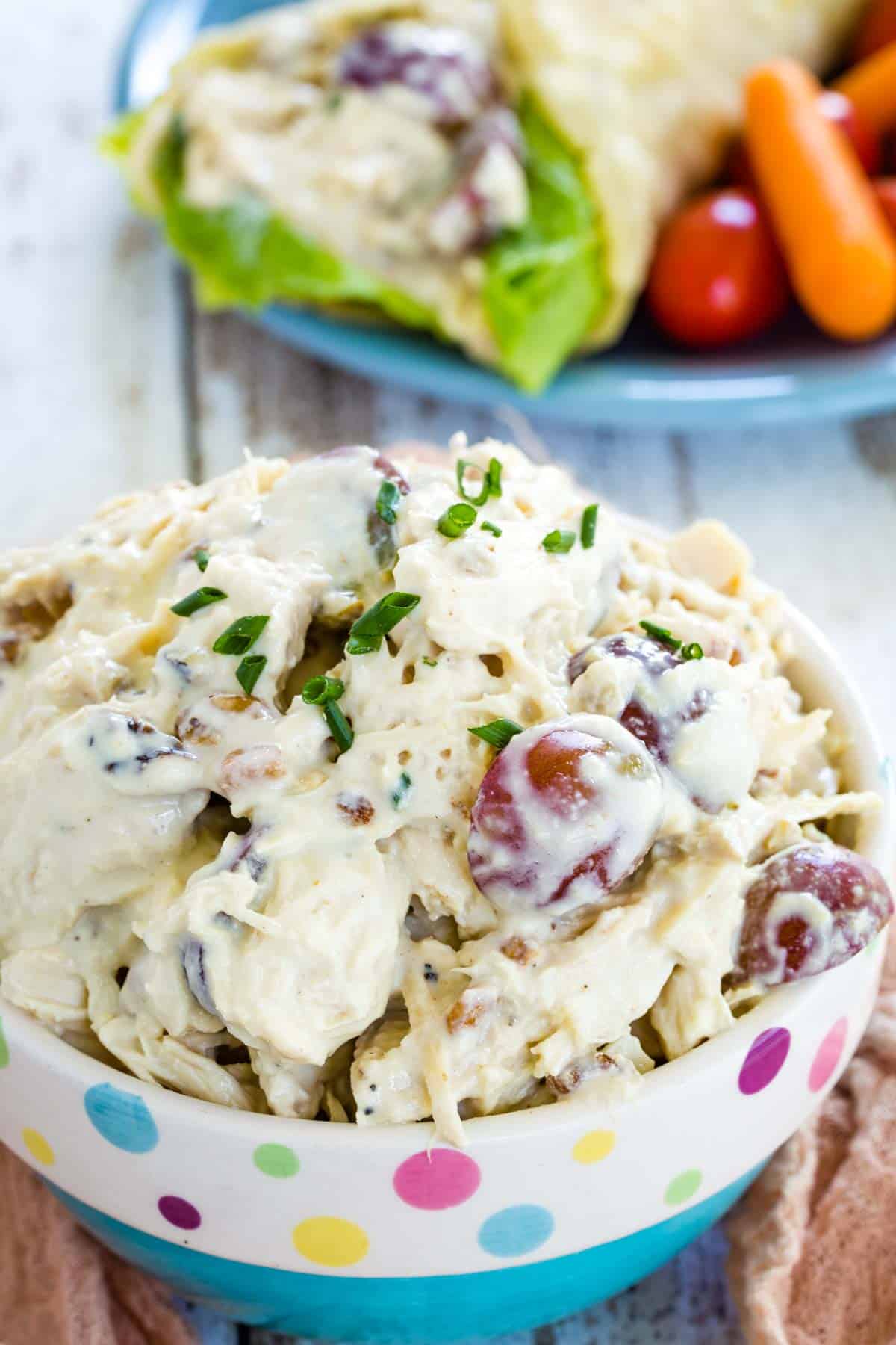 A decorative bowl of waldorf chicken salad garnished with chives.