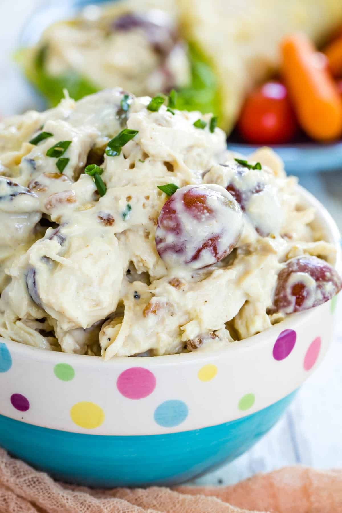 Chicken salad with grapes in a blue bowl that has a polka dot rim.