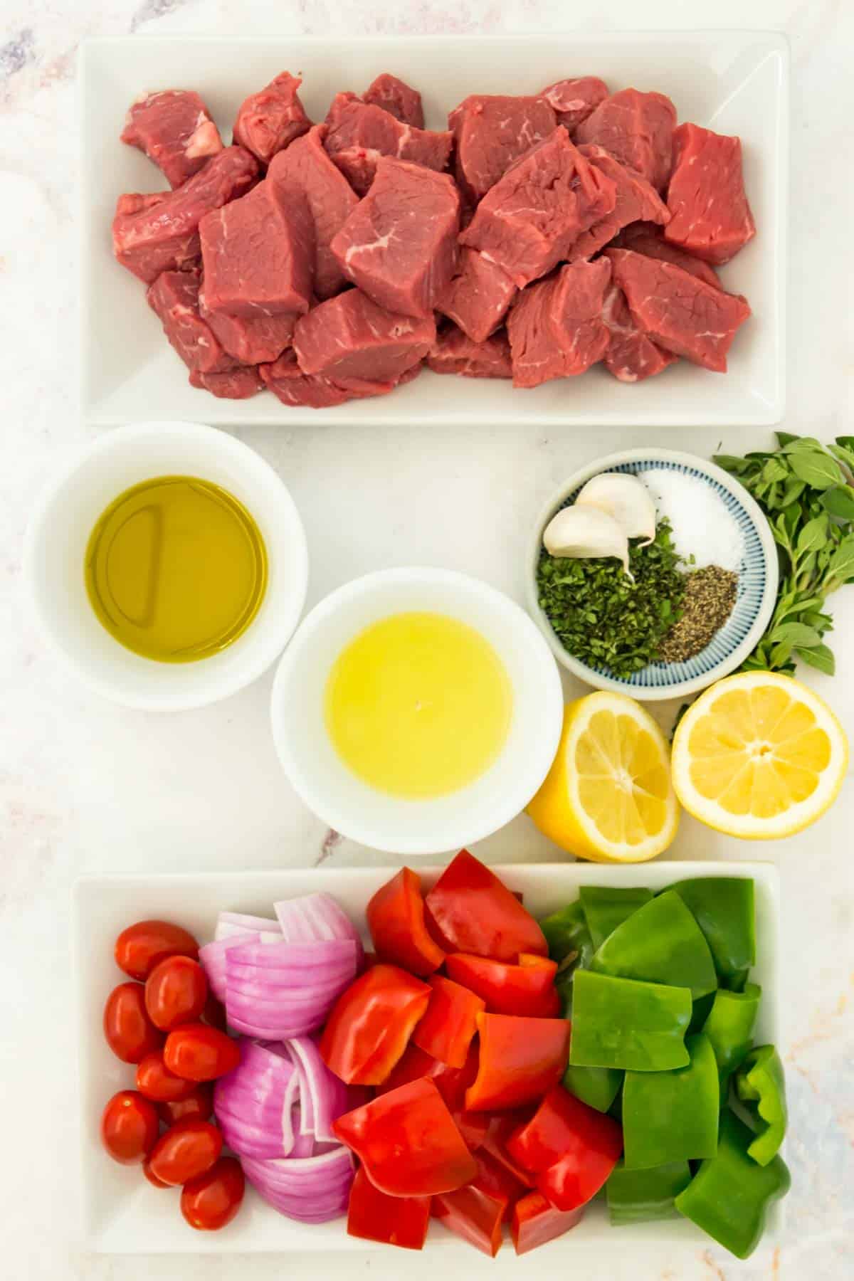 A plate of beef cubes, cut vegetables and marinade ingredients.