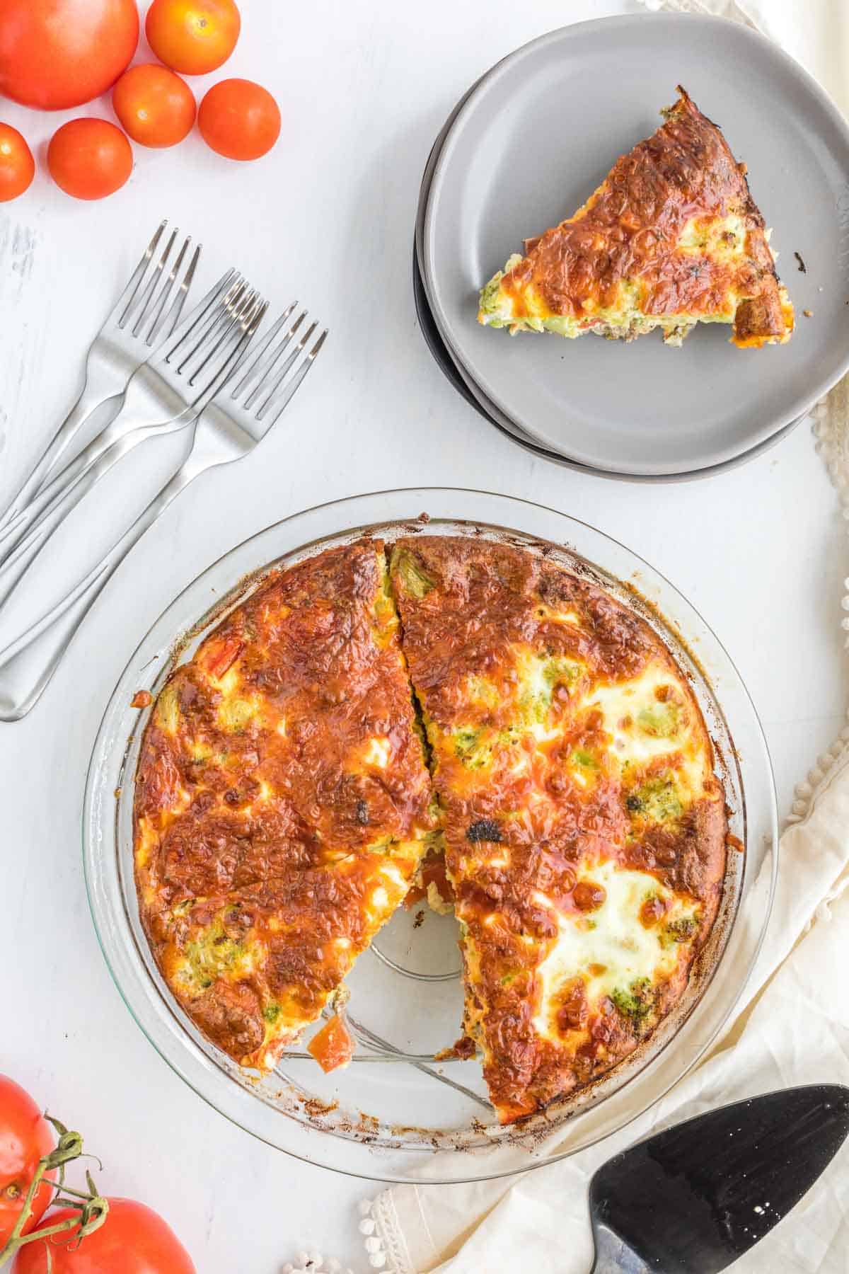 A bird's eye view of a quiche that's missing one slice next to a plate with the missing slice on it.