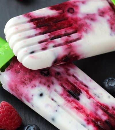 Two mixed berry popsicles laying on top of each other.