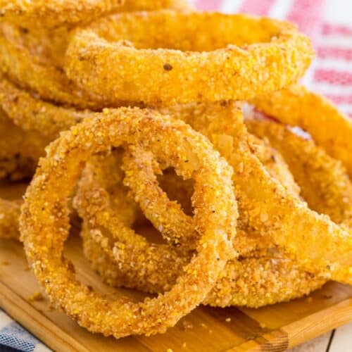 A pile of onion rings on a wooden platter.