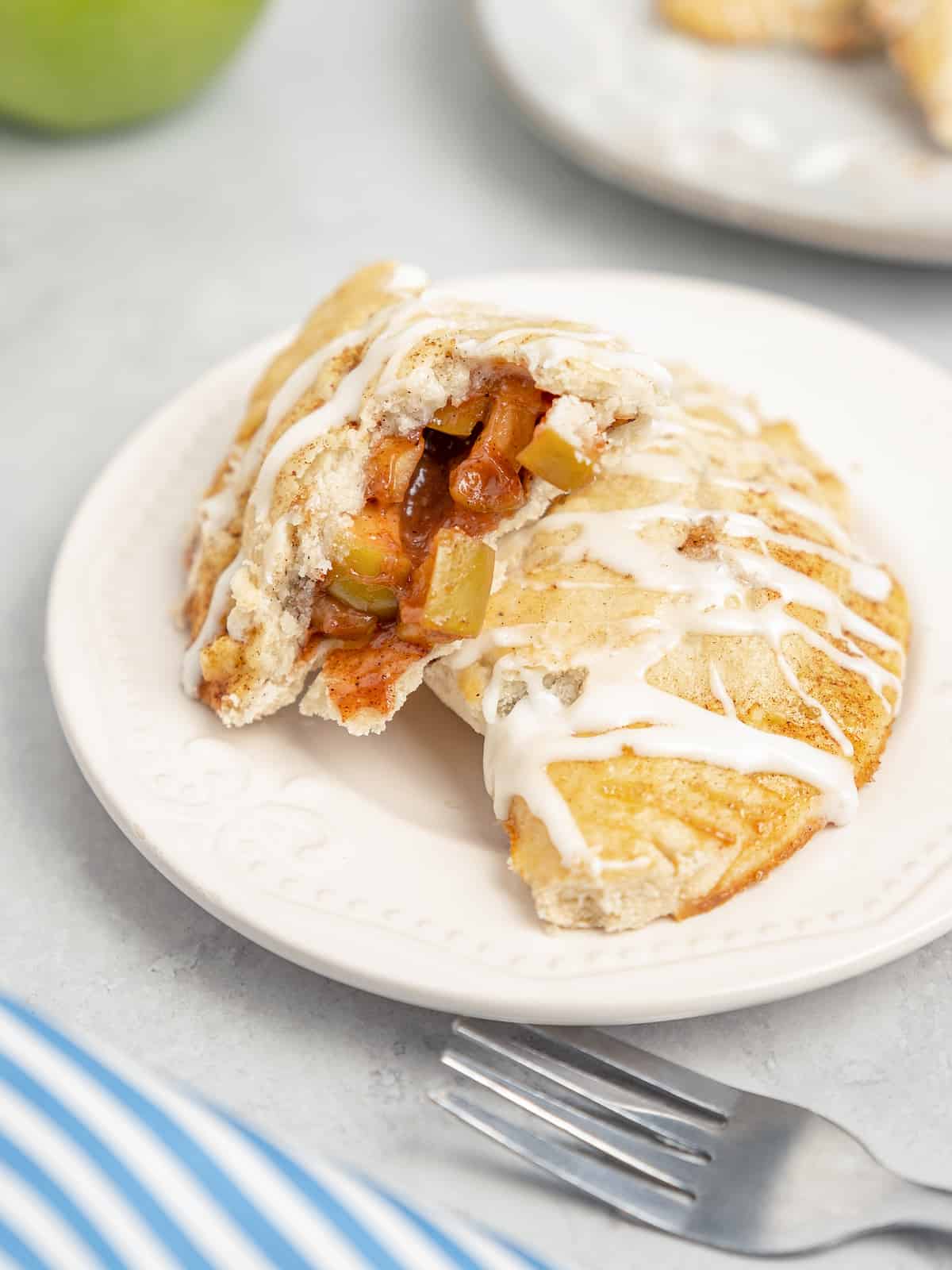 Two halves of an apple turnover on a white plate.