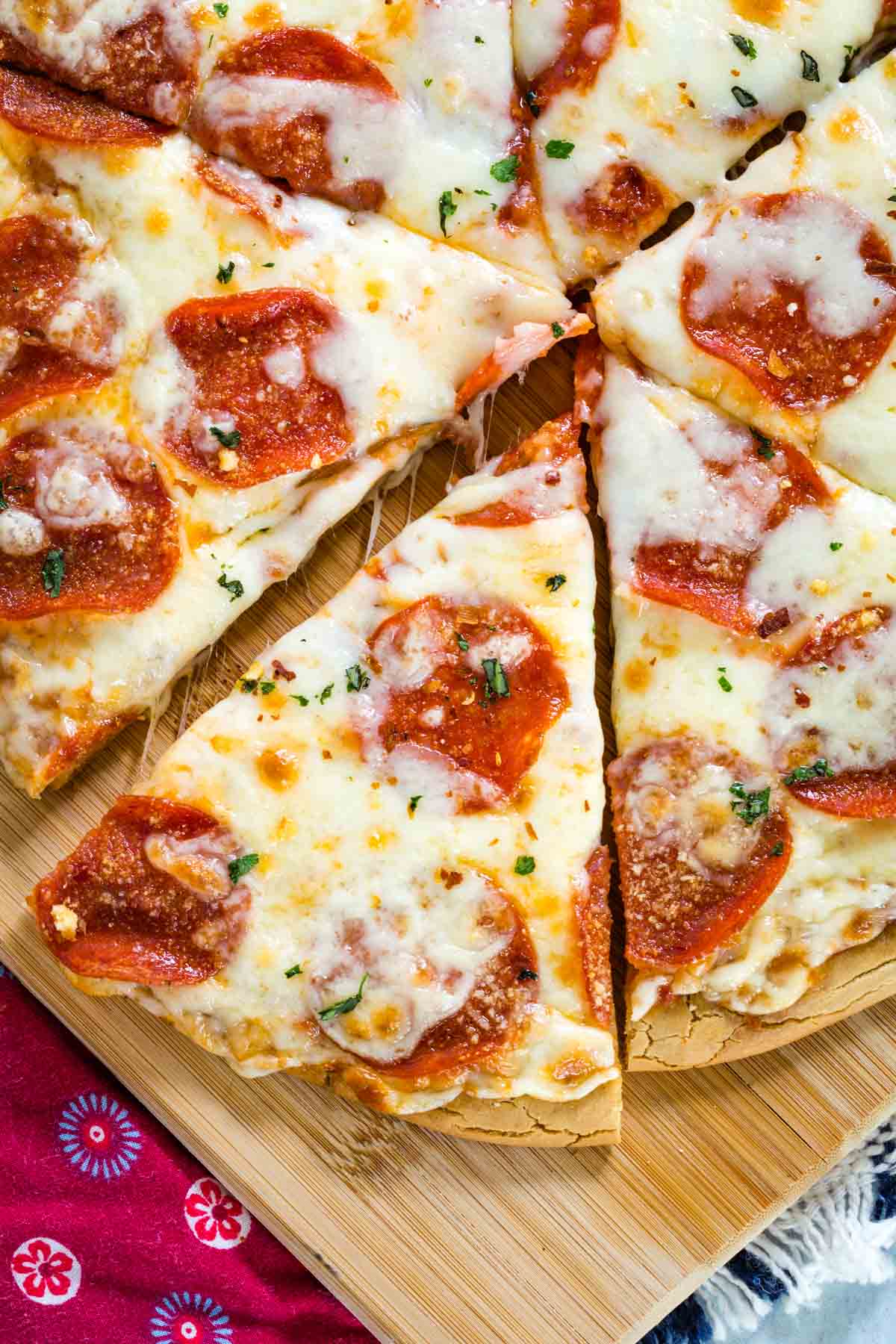 Top view of gluten free pepperoni pizza slices on a wooden cutting board.