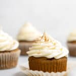 Side view of gluten free pumpkin cupcakes topped with swirls of cream cheese frosting.