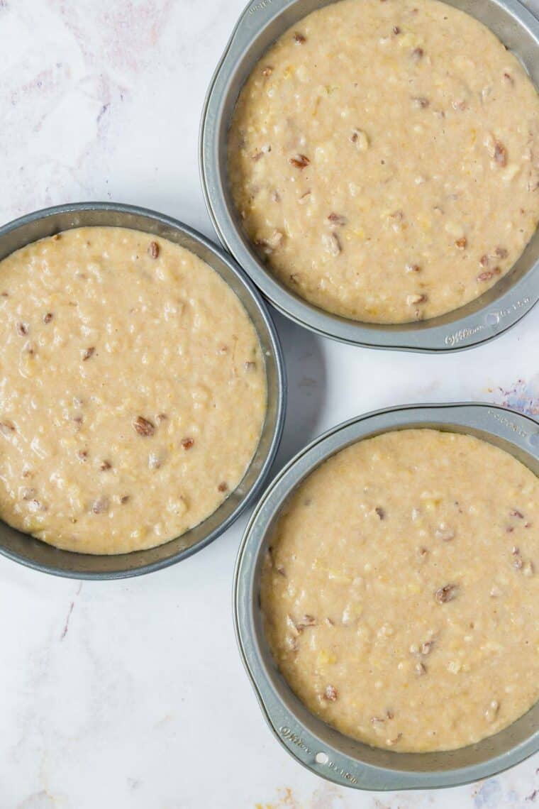 Three cake pans filled with batter.