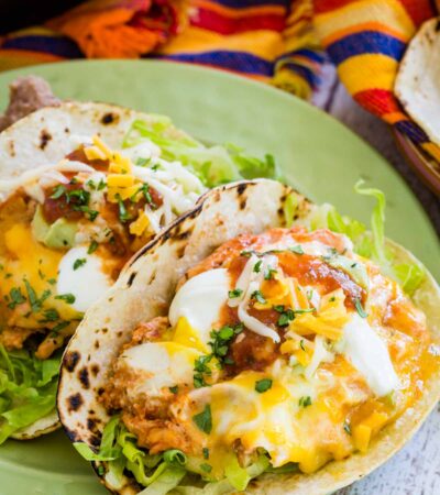 Two Mexican breakfast tacos filled with salsa eggs on a green plate.