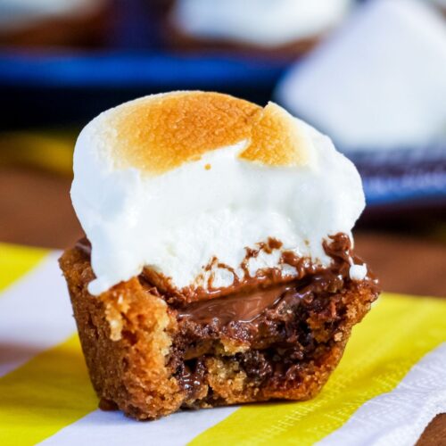 A chocolate chip cookie cup with melty chocolate and a toasted marshmallow on top with a bite taken out.