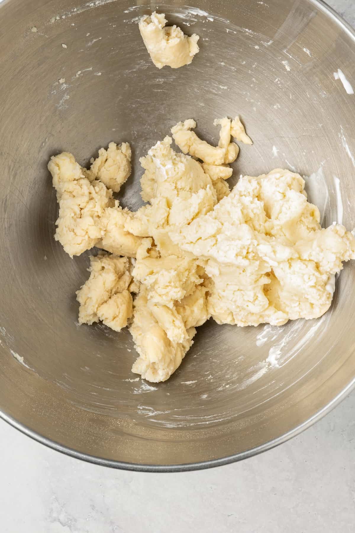 Gluten free pizza dough in the bottom of a metal mixing bowl.