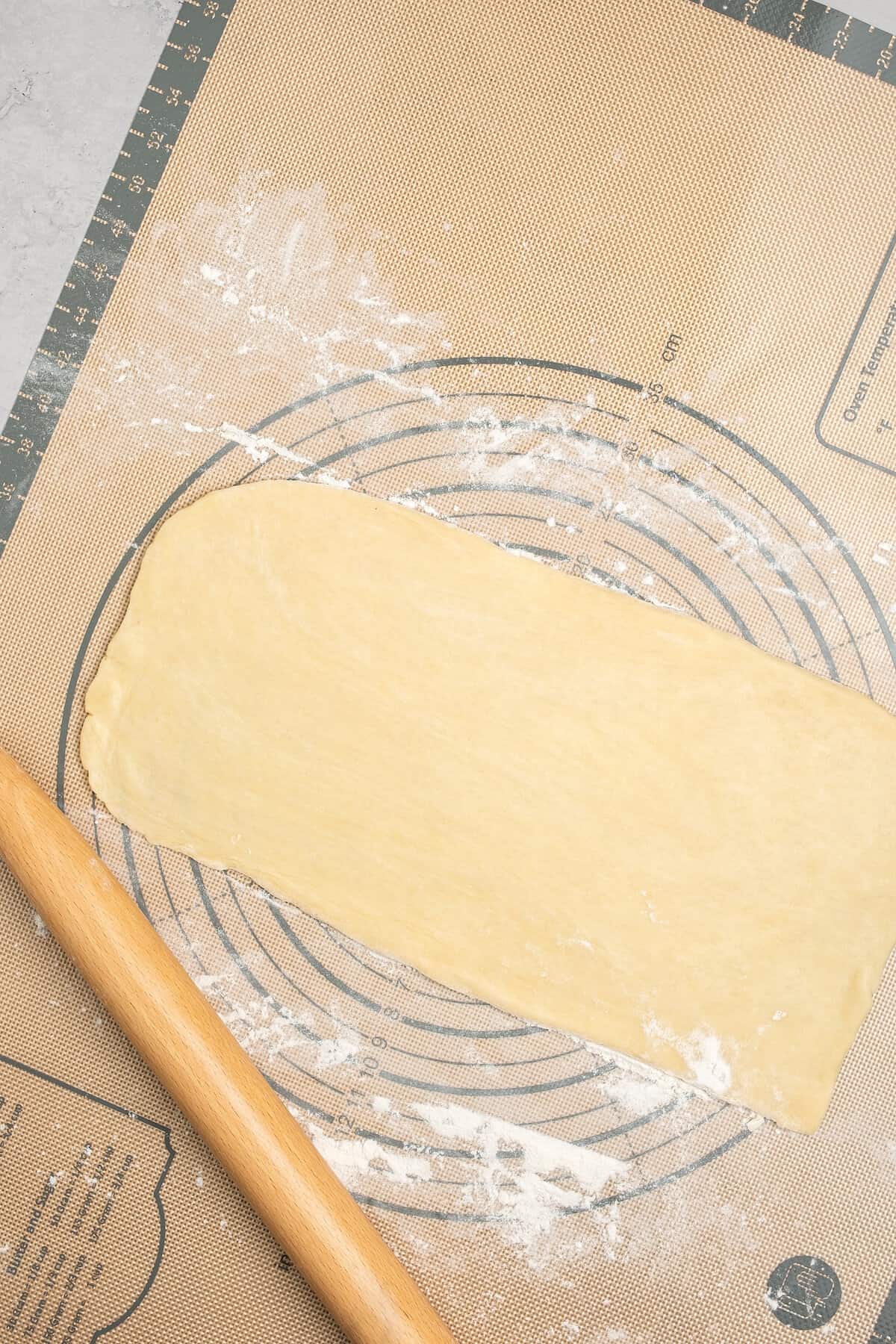 Gluten free pizza dough rolled out on a floured work surface.