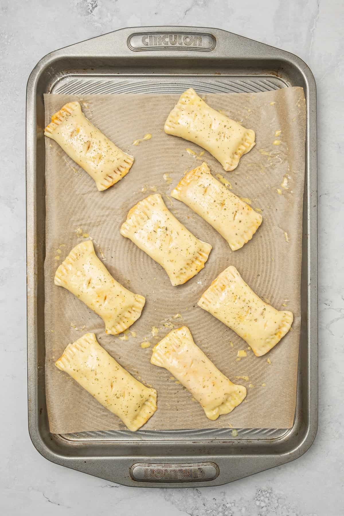 Overhead view of gluten free pizza rolls arranged on a baking sheet, ready to be air fried.