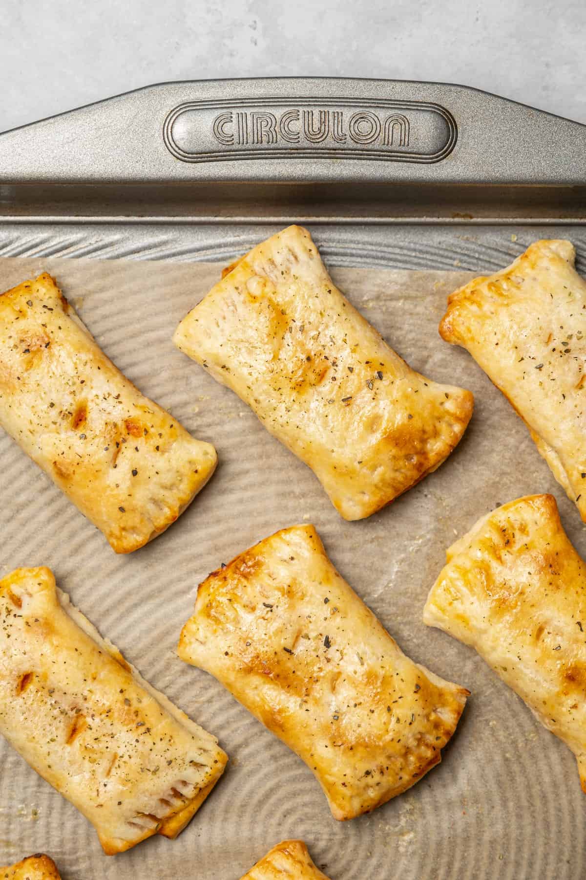 Overhead view of crispy air fryer pizza rolls on a parchment-lined baking sheet.