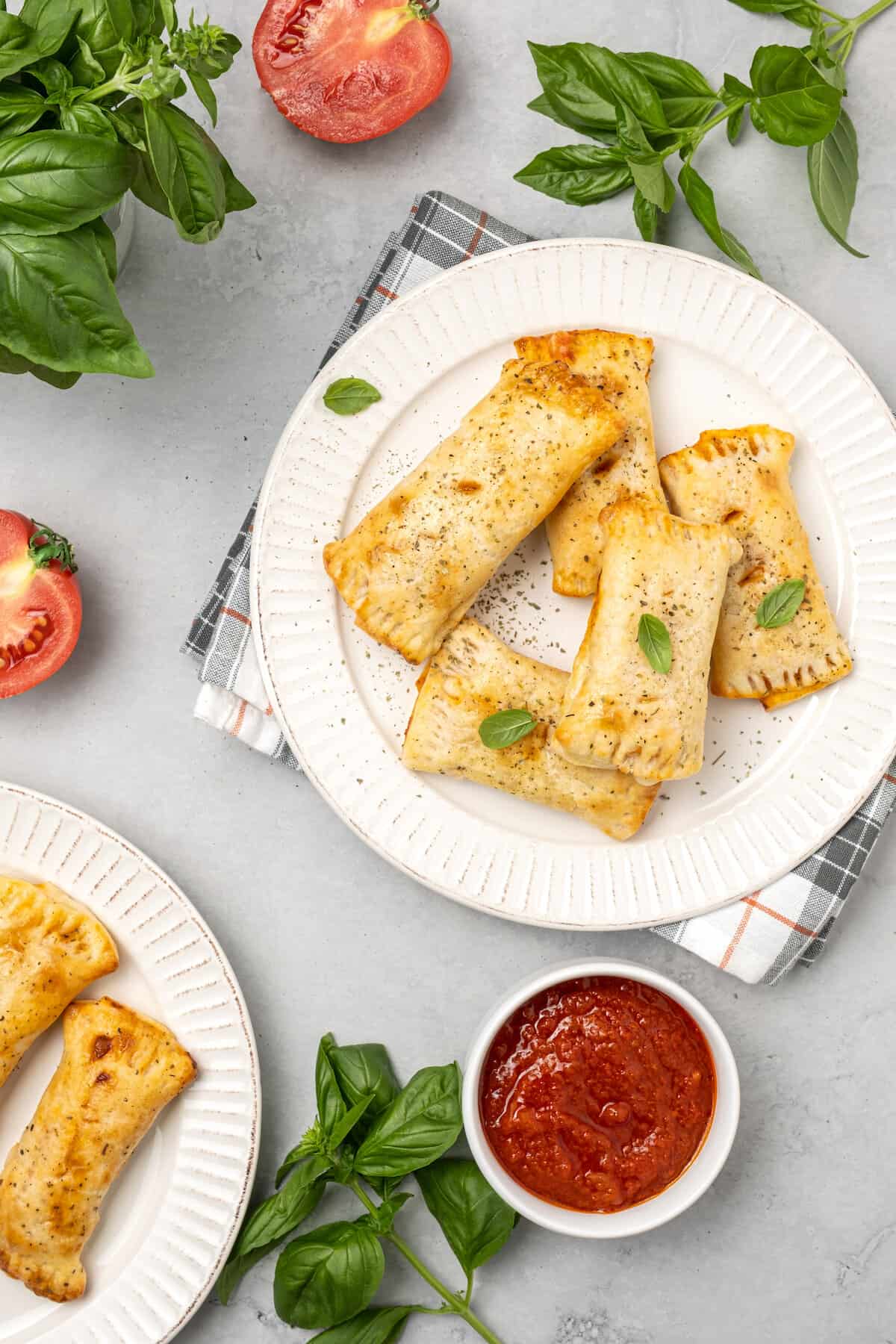 Overhead view of air fryer gluten free pizza rolls on a white plate, next to a bowl of marinara sauce for dipping.