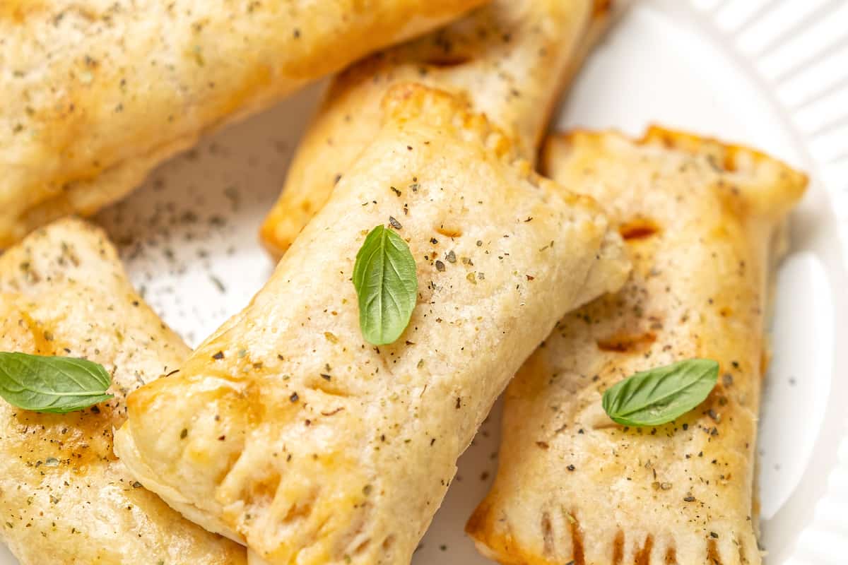 Closeup of pizza rolls piled on a plate and garnished with basil leaves.