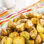 crispy air fryer potatoes in a white dish on top of a striped napkin and a piece of burlap.