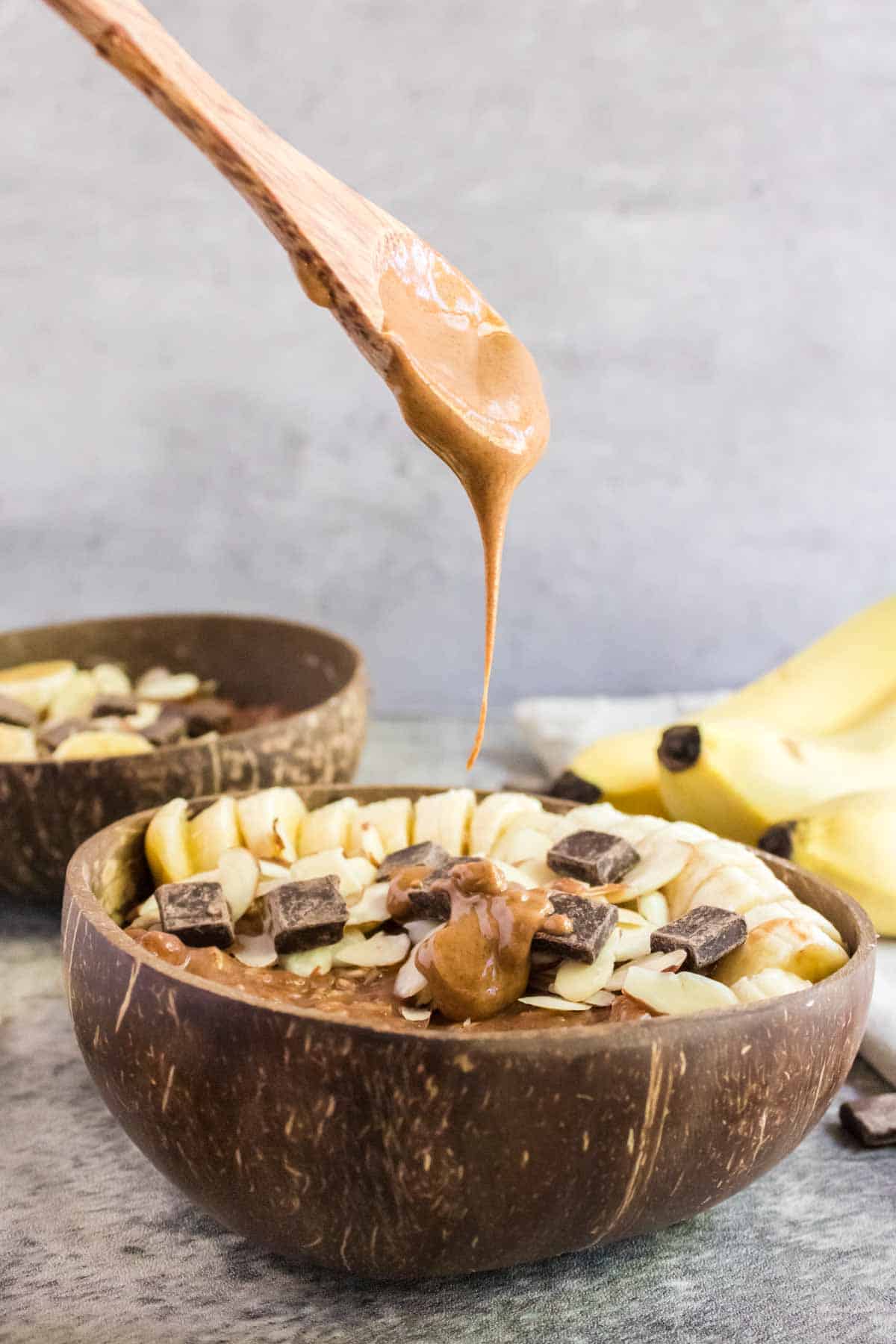 Almond butter being drizzled on top of a bowl of chocolate oatmeal.