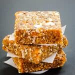 Three apricot chia energy bars stacked with squares of wax paper between each one.
