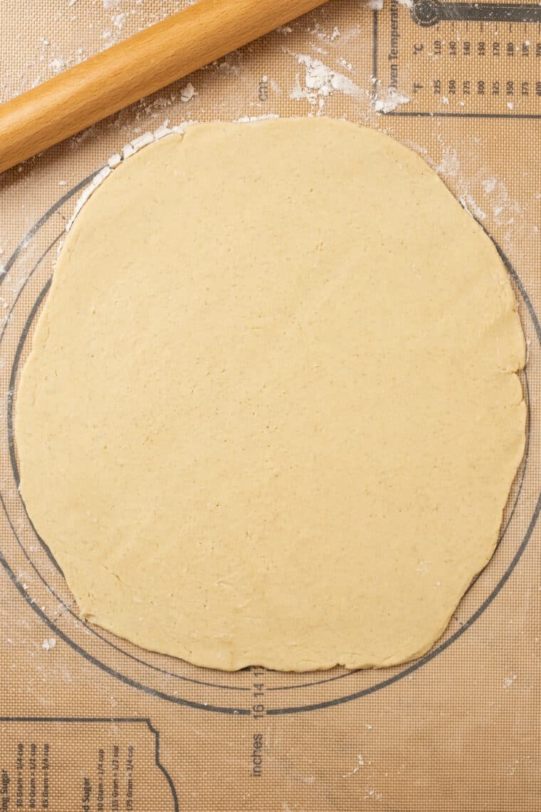 Gluten free dough rolled into a thin circle on a floured surface.
