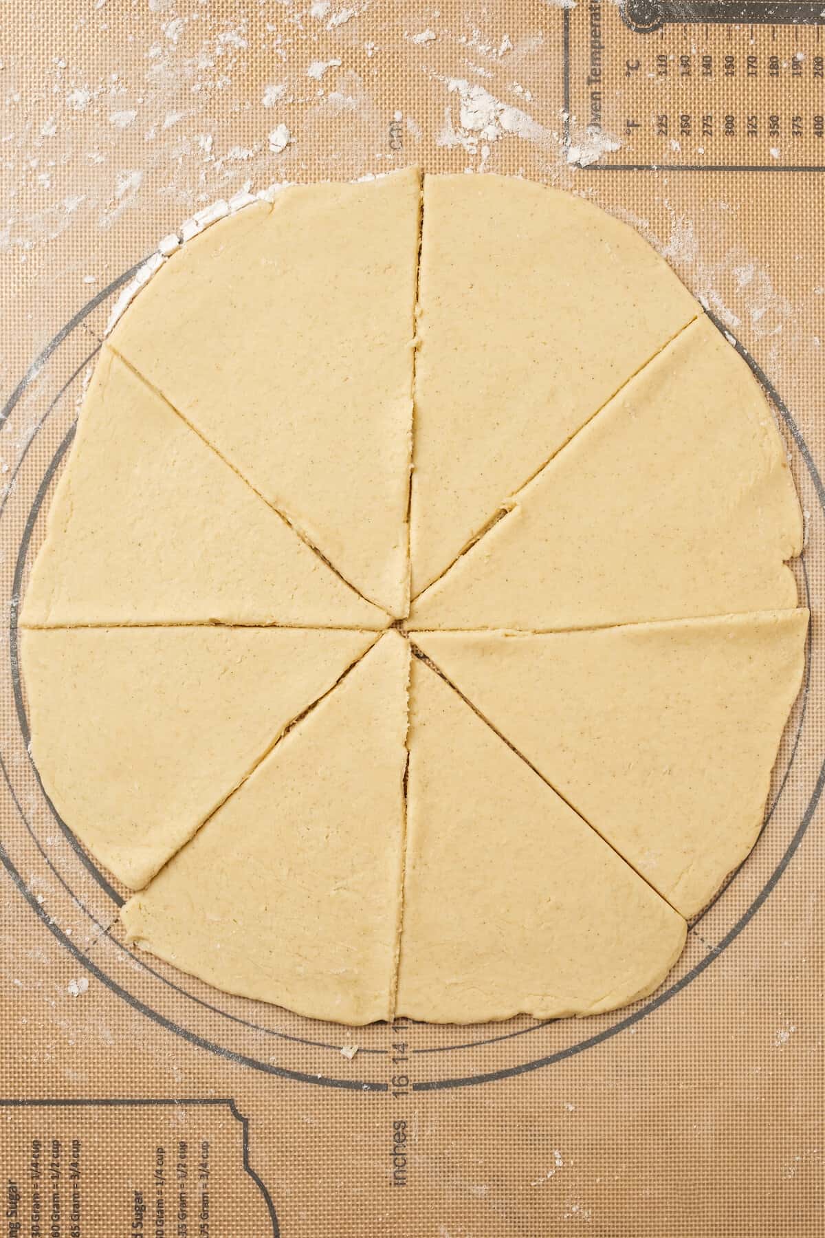 A thin dough circle cut into eight triangles on a floured surface.