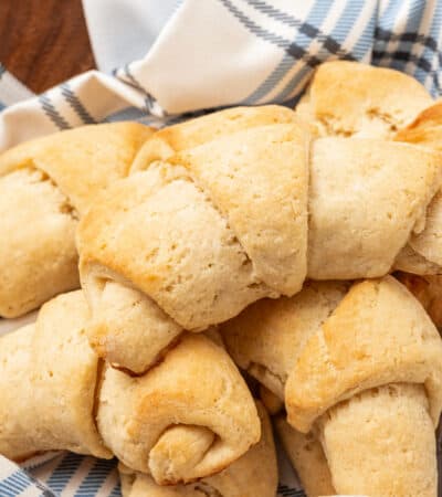 Assorted gluten free crescent rolls nestled in a bowl lined with a dishcloth.