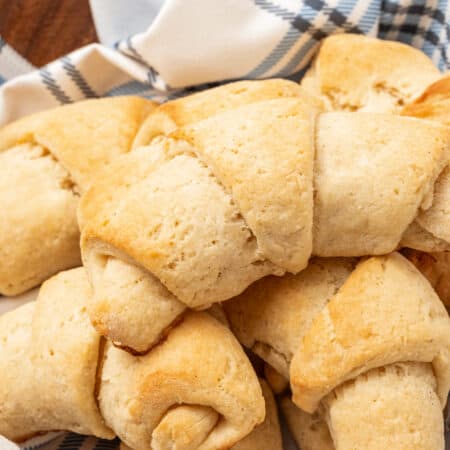 Assorted gluten free crescent rolls nestled in a bowl lined with a dishcloth.