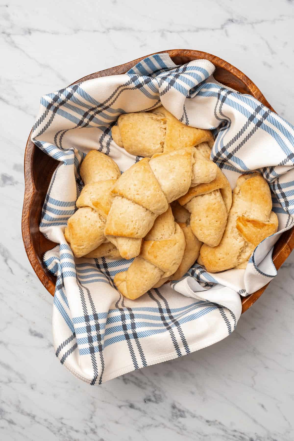 Top view of assorted gluten free crescent rolls nestled in a bowl lined with a dishcloth.