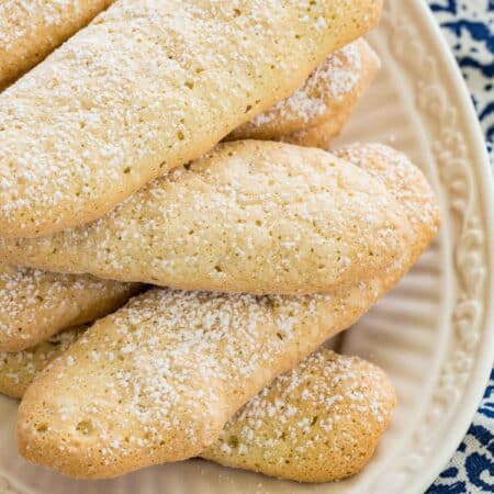 Top view of gluten free ladyfingers stacked on a white plate.