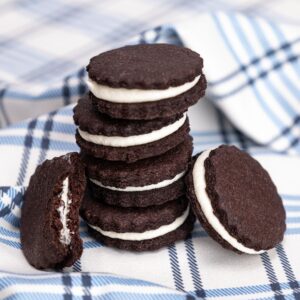 A stack of four homemade oreos with two leaning against the stack, one with a bite taken out of it.