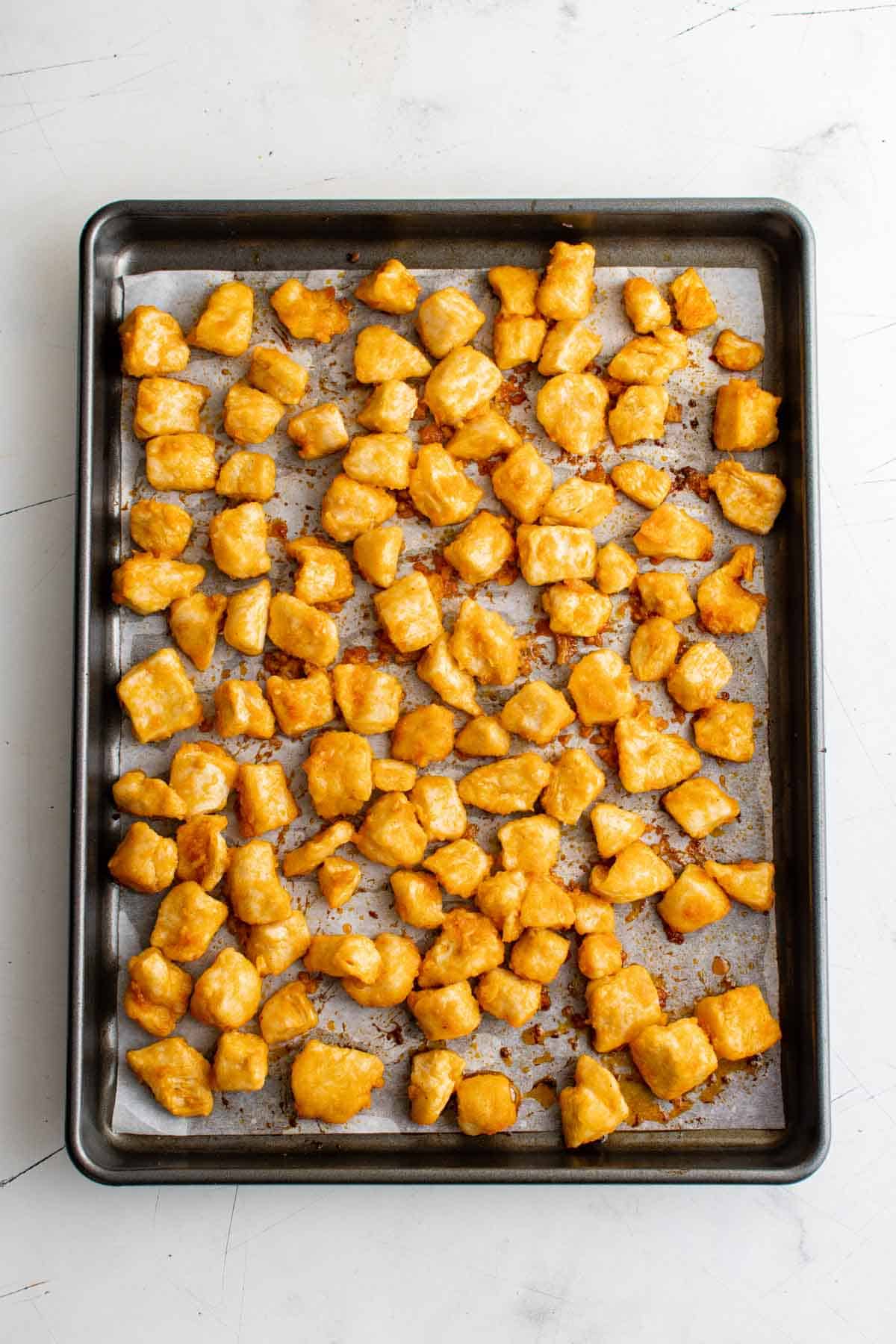 Top view of baked buffalo chicken bites on a metal baking sheet.