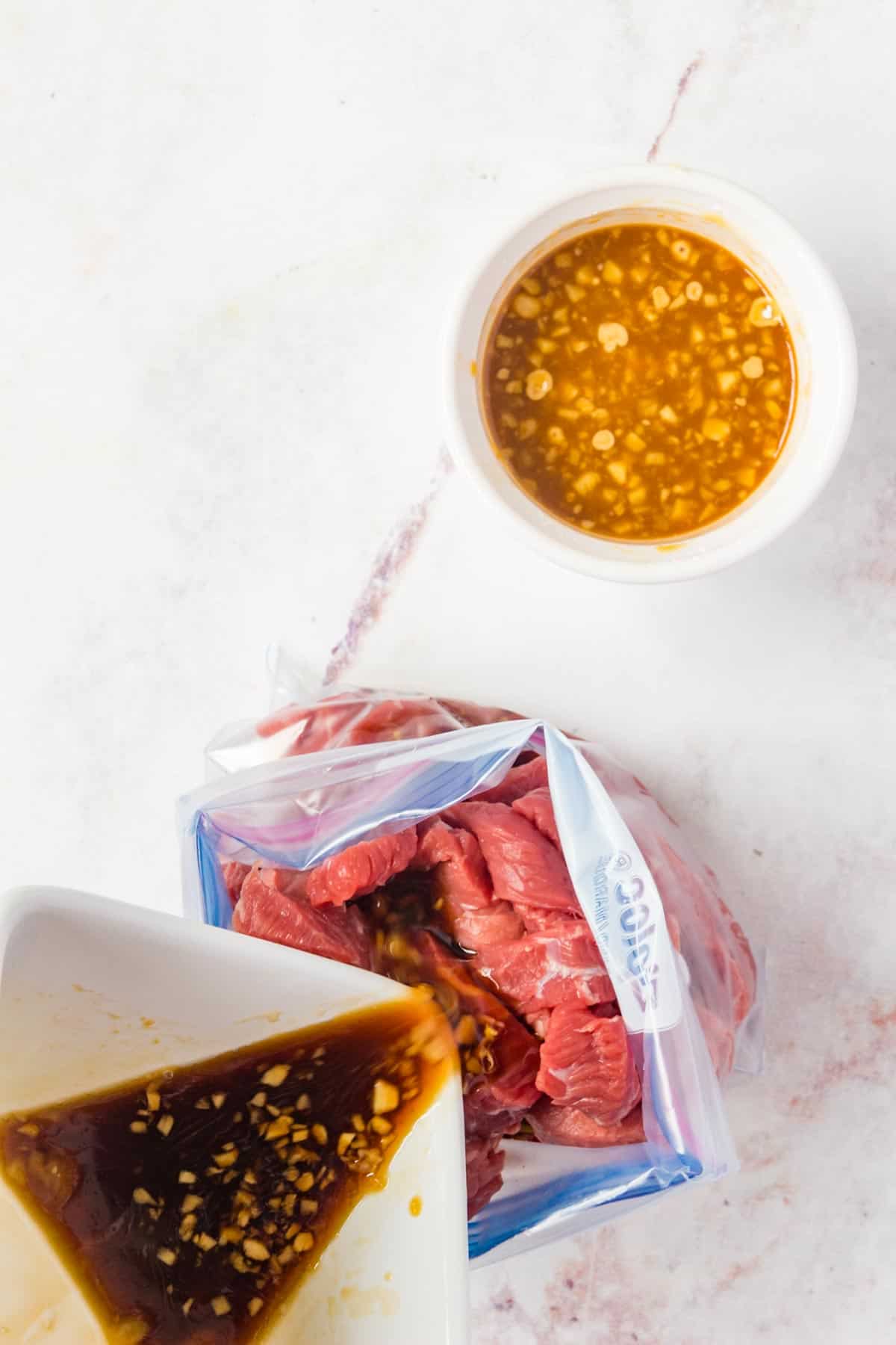 Pouring the marinade into the plastic bag with the sliced beef.