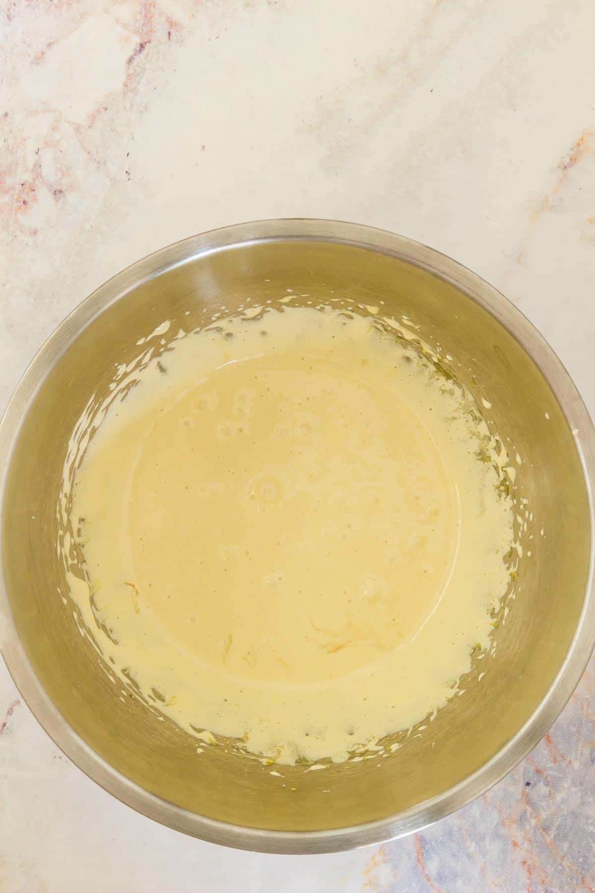 Beaten egg yolks and sugar in a metal mixing bowl.