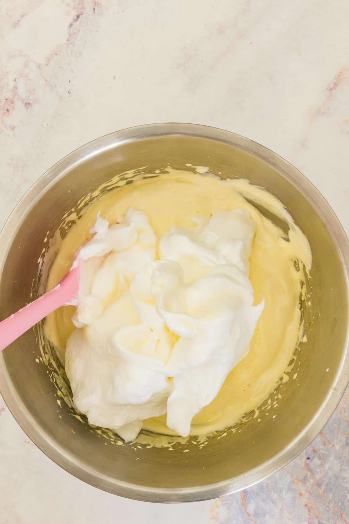 Meringue is folded into the beaten egg yolk mixture for gluten free ladyfinger batter.