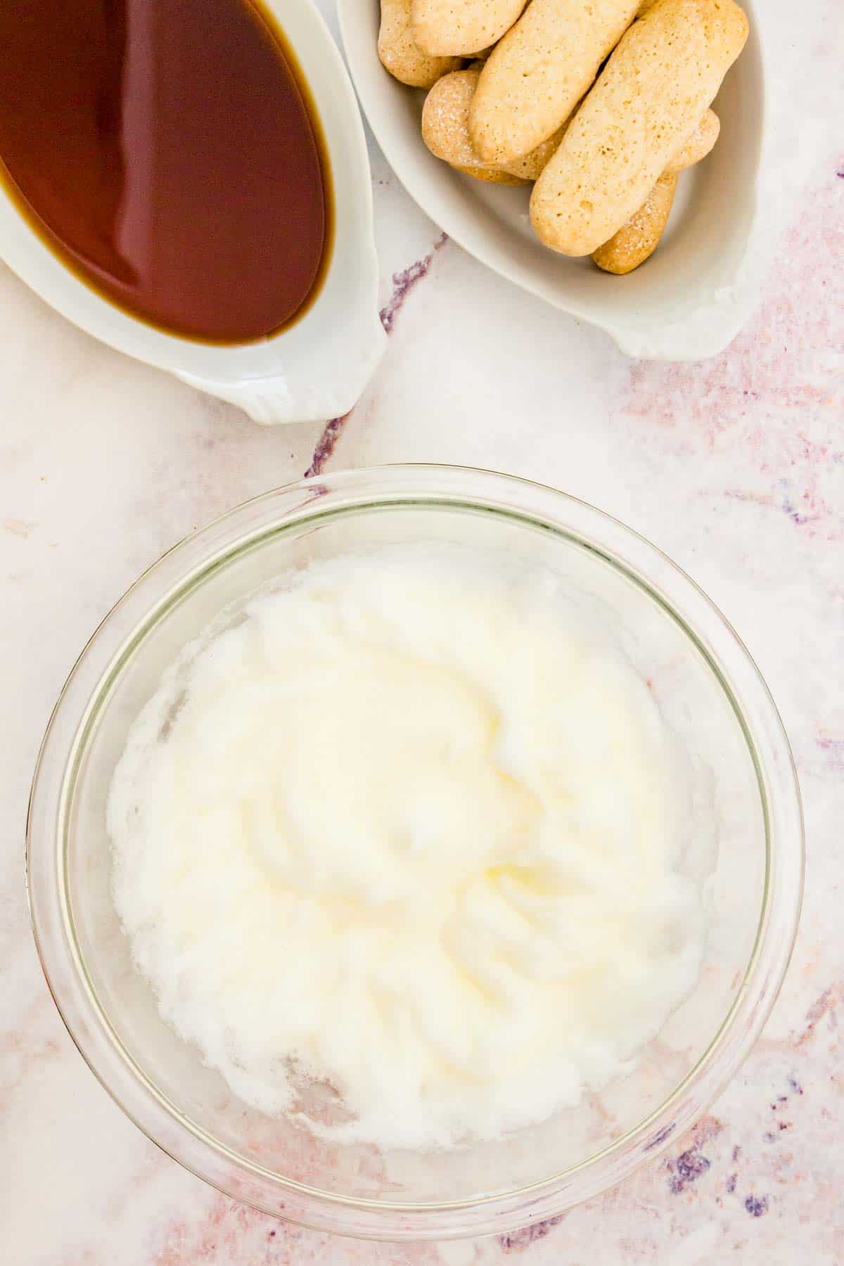 Whipped egg whites in a glass mixing bowl.