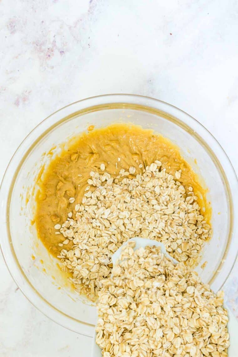 Pouring oats into the bowl of wet ingredients.