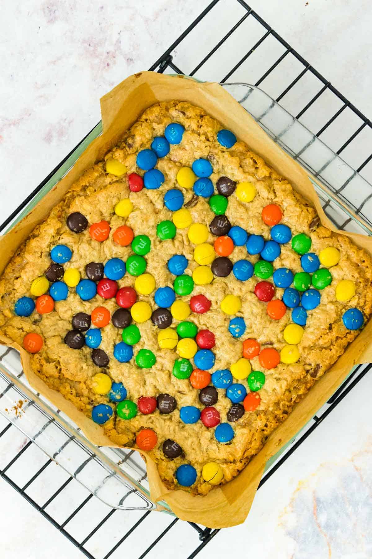 A baked pan of monster cookie bars on a cooling rack.