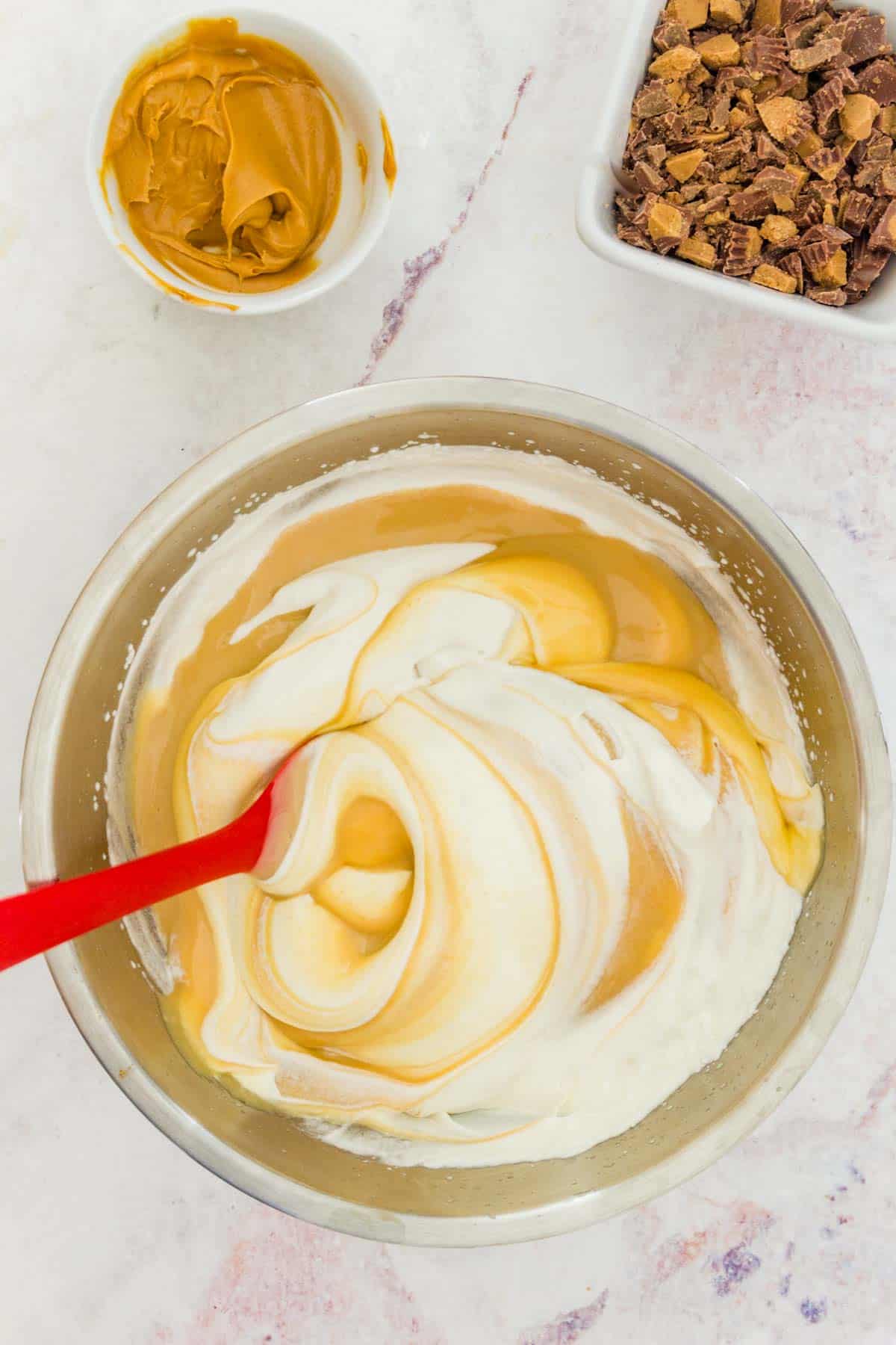 The sweetened condensed milk mixture is stirred into the whipped cream for the Reese's ice cream base.