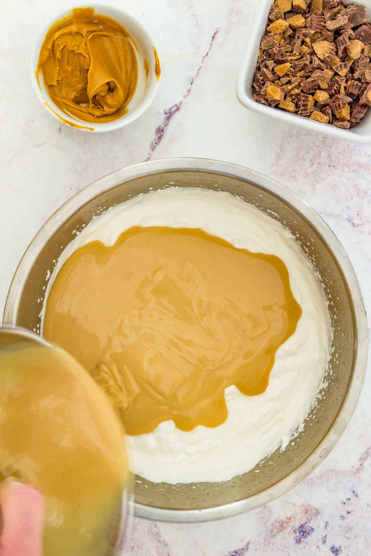 Peanut butter and condensed milk being added to whipped cream.