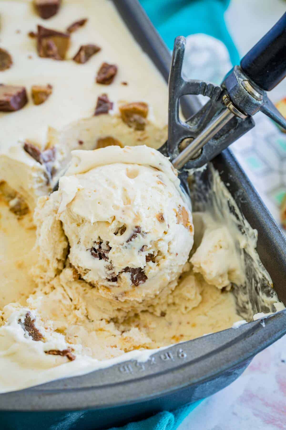 No-churn Reese's ice cream is scooped from a loaf pan with a large ice cream scoop.