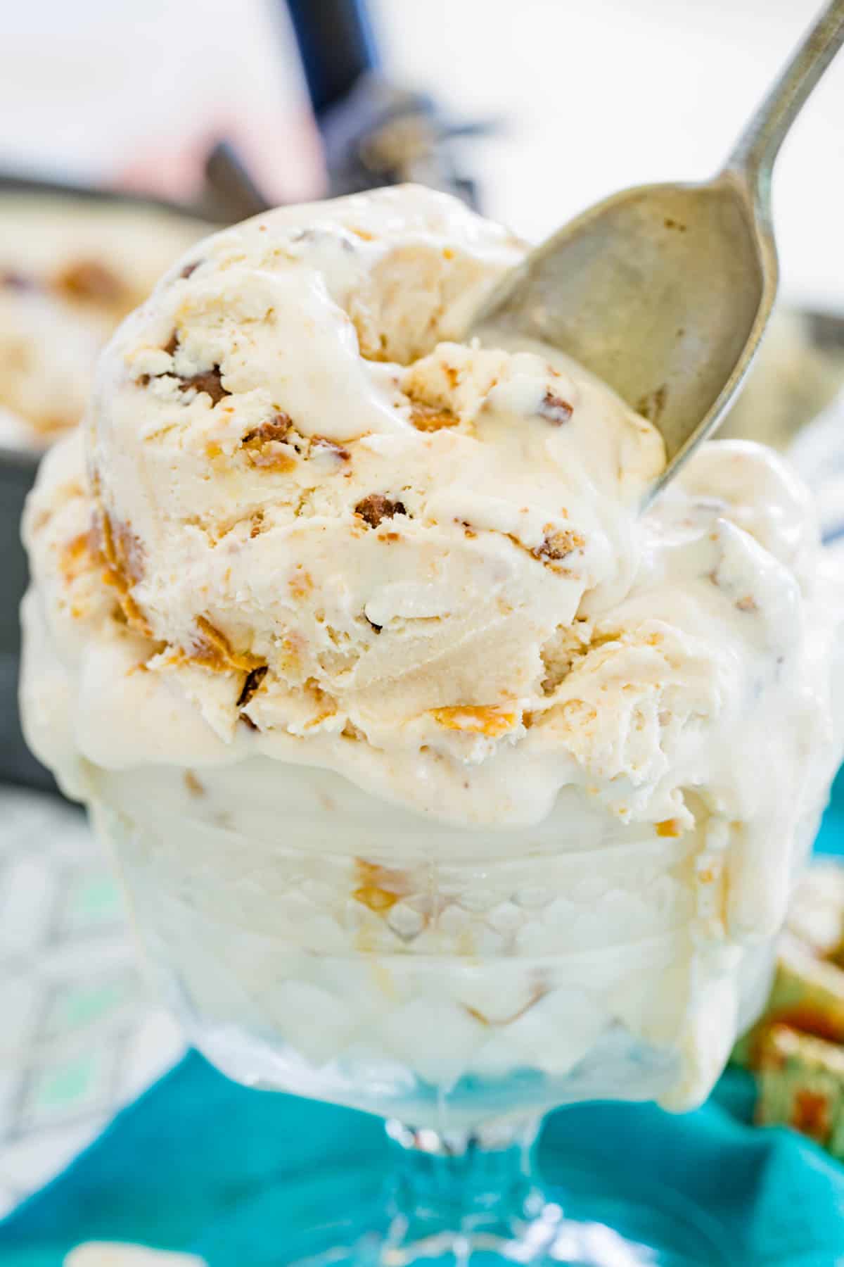 A spoon stuck into a scoop of no-churn Reese's ice cream in a glass ice cream dish.