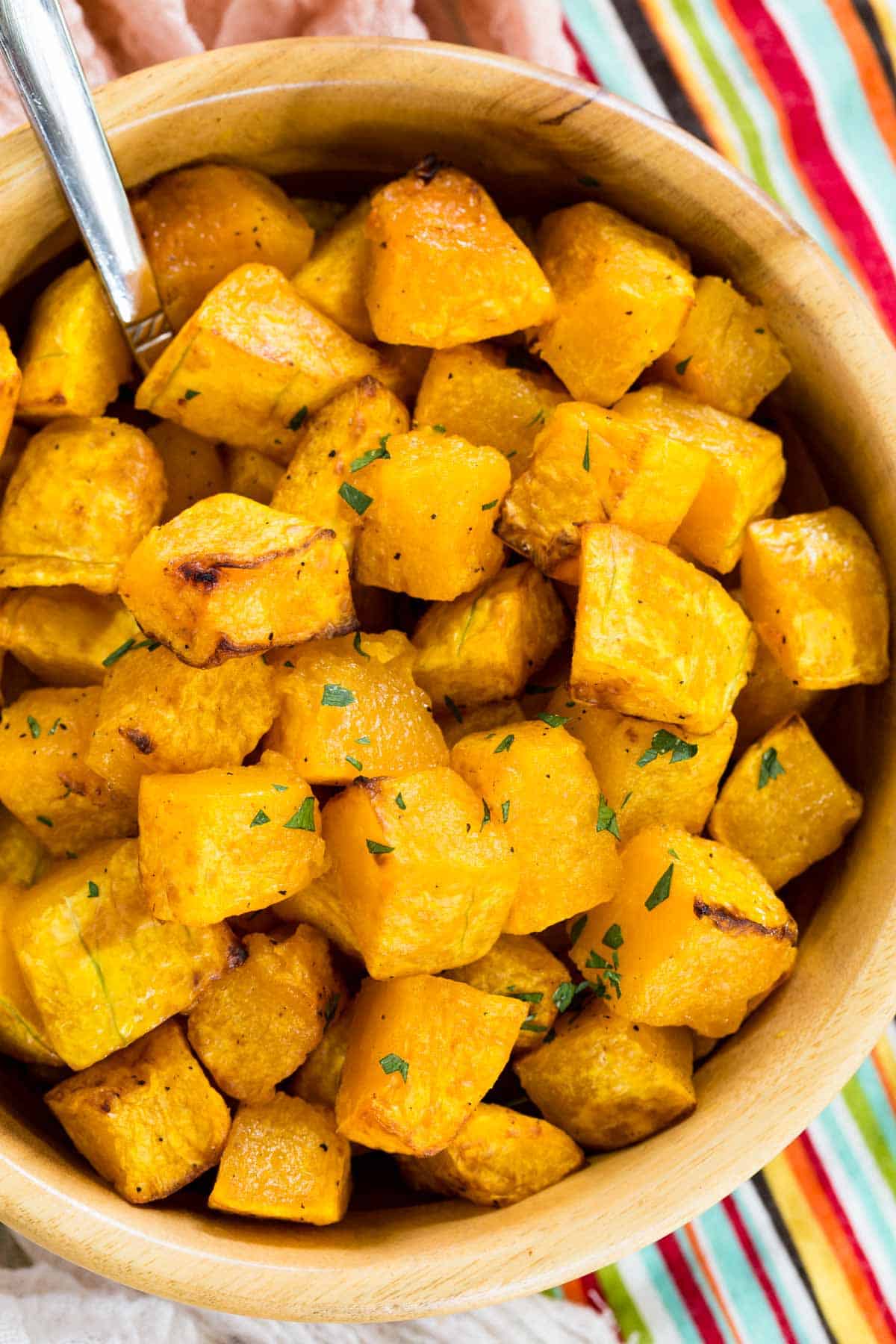 A spoon stuck into a bowl of cubed air fryer butternut squash.