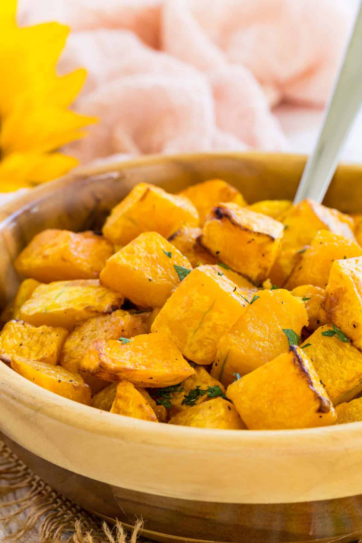 A spoon stuck into a bowl of cubed air fryer butternut squash.